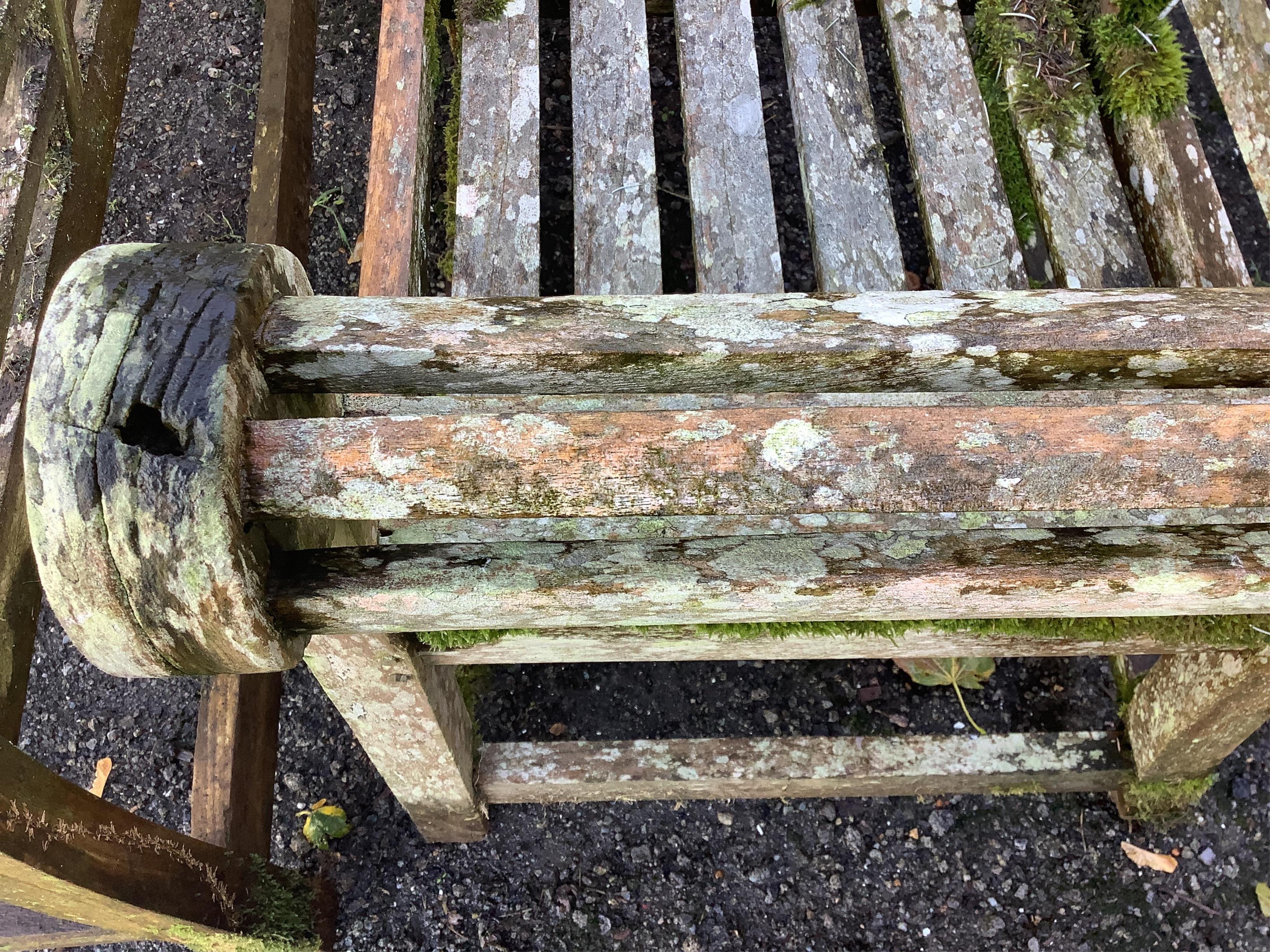 A weathered teak Lutyens style garden bench, width 165cm, depth 58cm, height 103cm. Condition - poor, covered in lichen